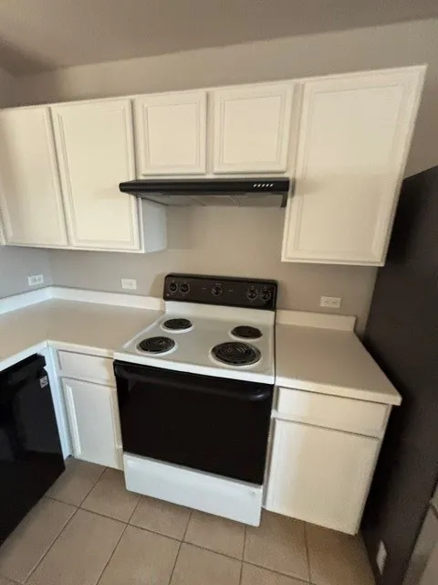 White cabinetry with a black range hood, a white electric range, and light-toned countertops