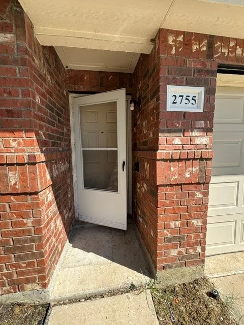 Brick exterior with a recessed entryway, featuring an overhead porch light and clear house numbering