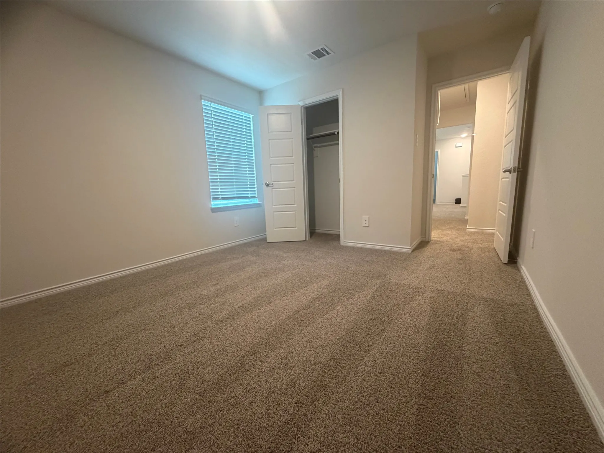 Bedroom 3- Neutral wall finishes, carpeted flooring, a window with horizontal blinds, and a built-in closet with a white paneled door