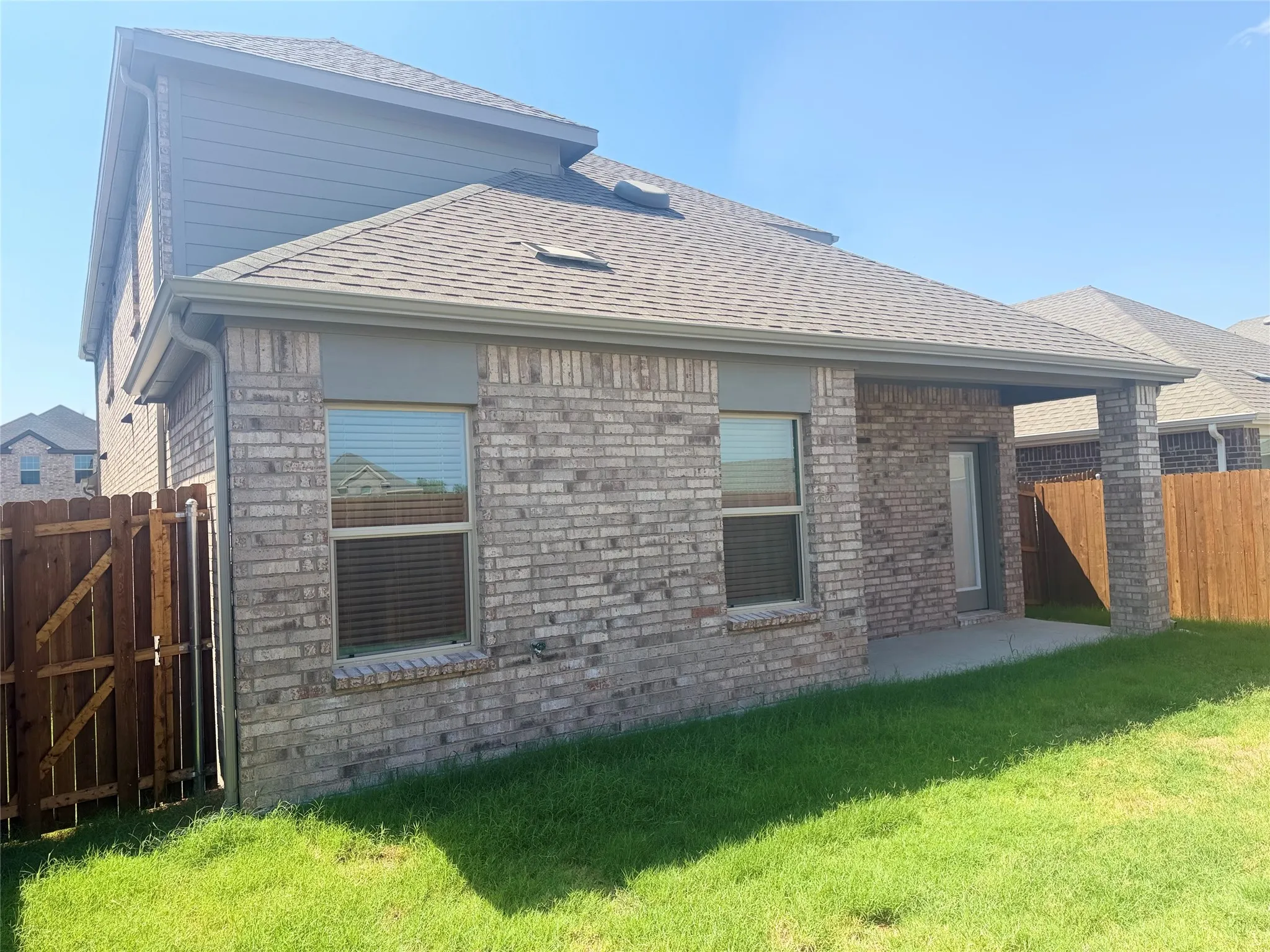 Brick exterior with covered patio, wood fencing, and second-story siding