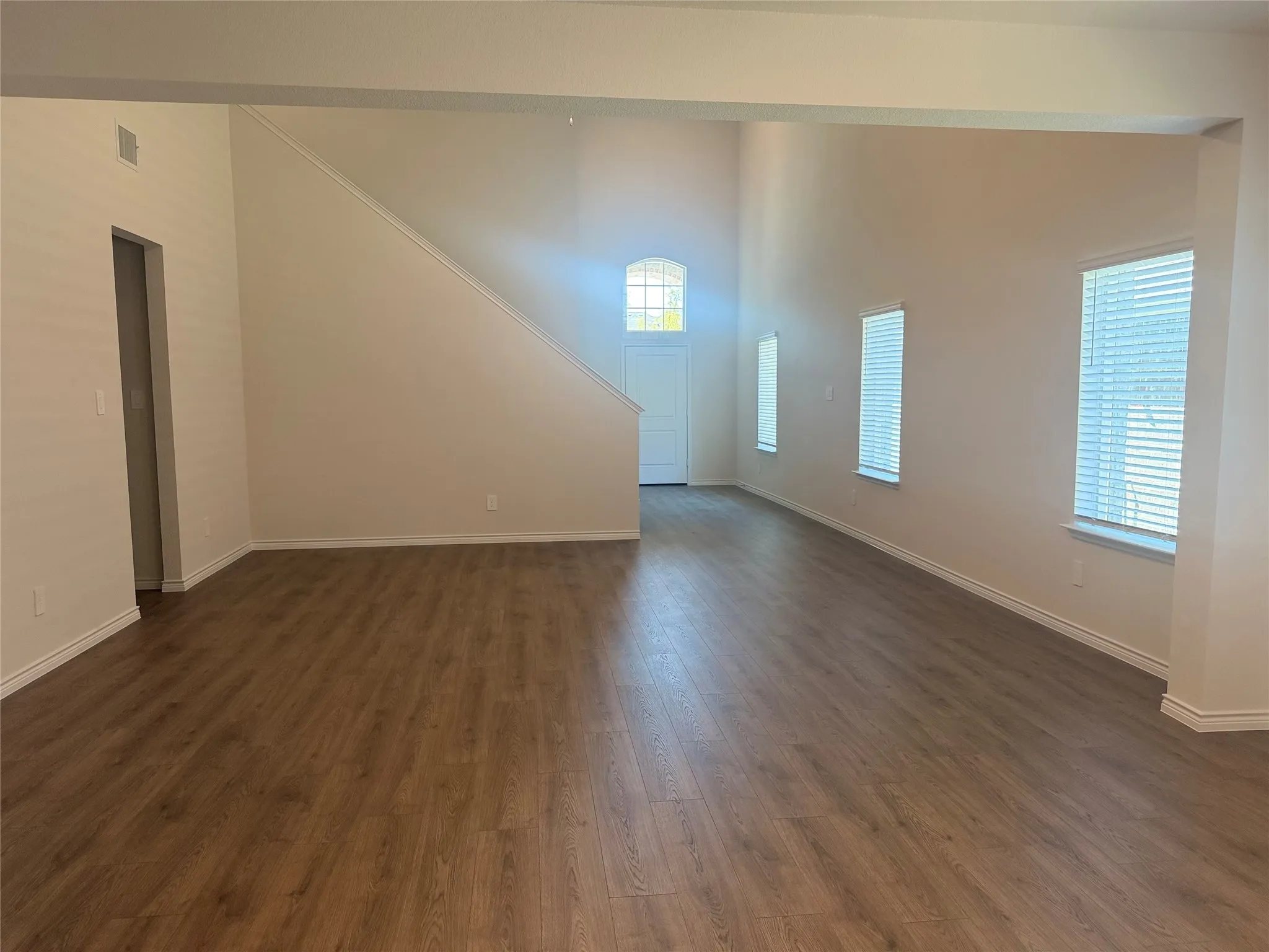 Vaulted ceilings, wood-finish flooring, multiple windows with blinds, and white trim