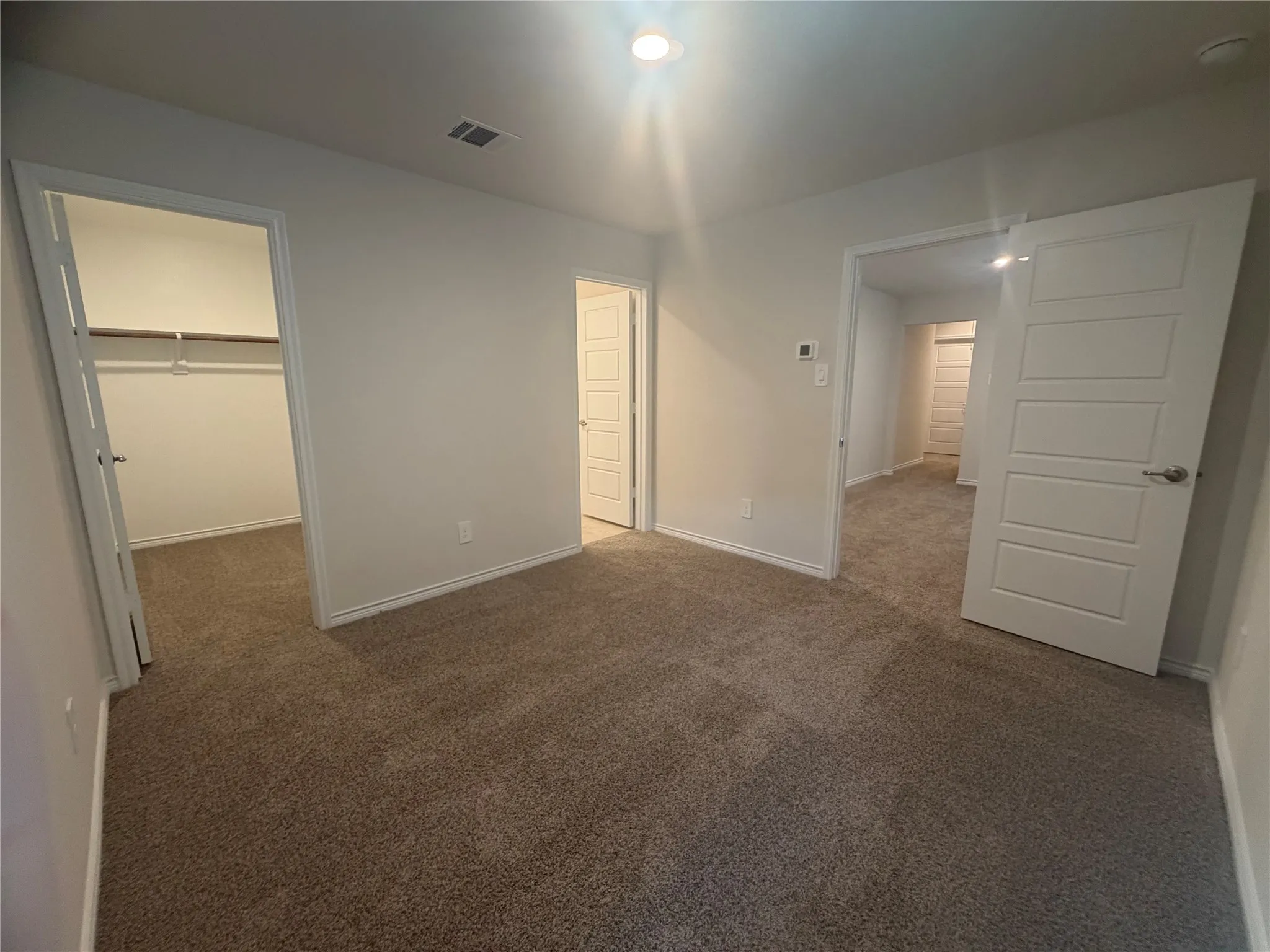 Bedroom 2- Carpeted room with recessed lighting, a walk-in closet, and a white panel door and a private ensuite full bathroom.
