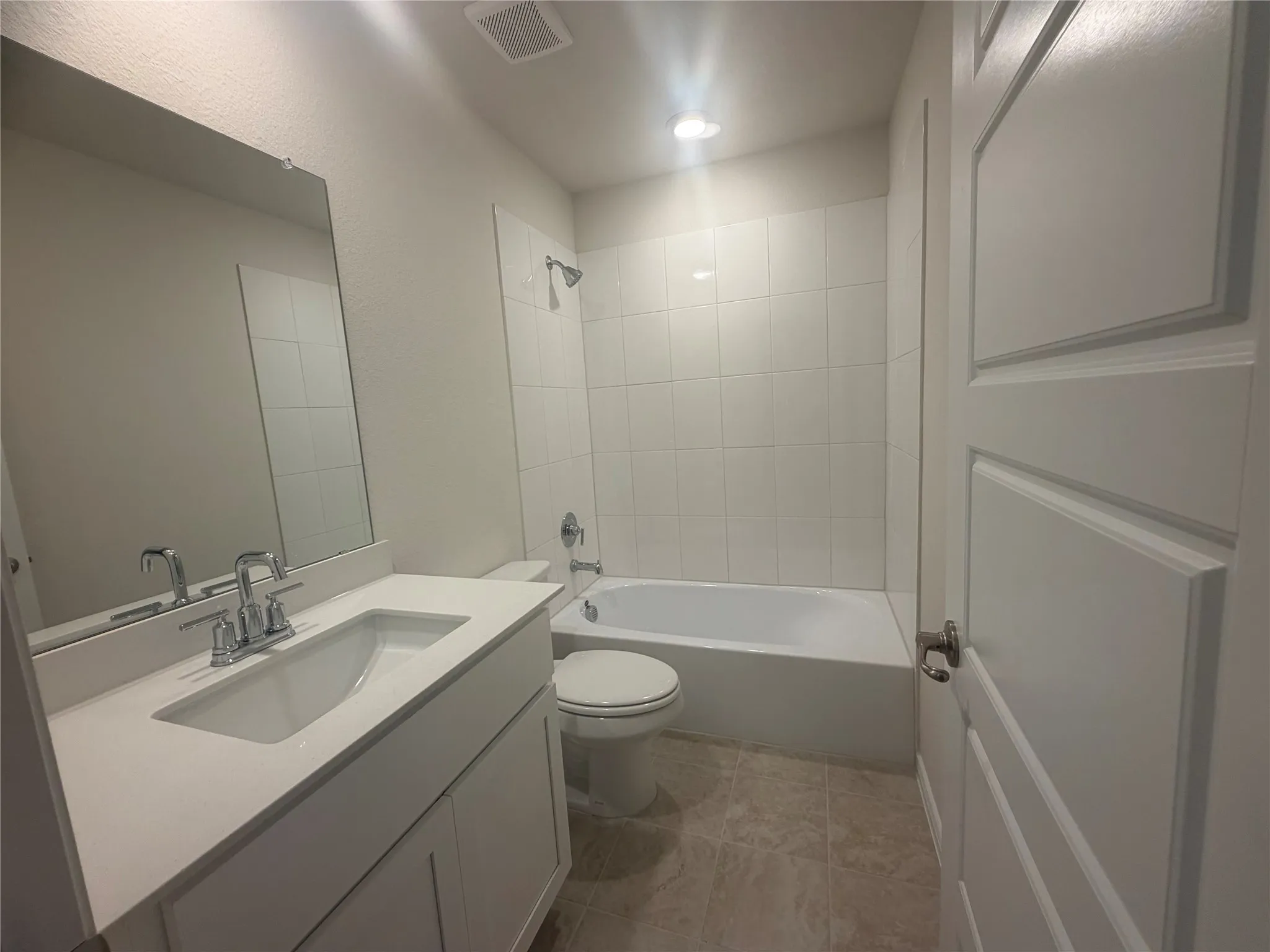 Bathroom featuring a single vanity with an integrated sink, chrome faucet, white paneled cabinetry, and a full bathtub with a tiled shower surround