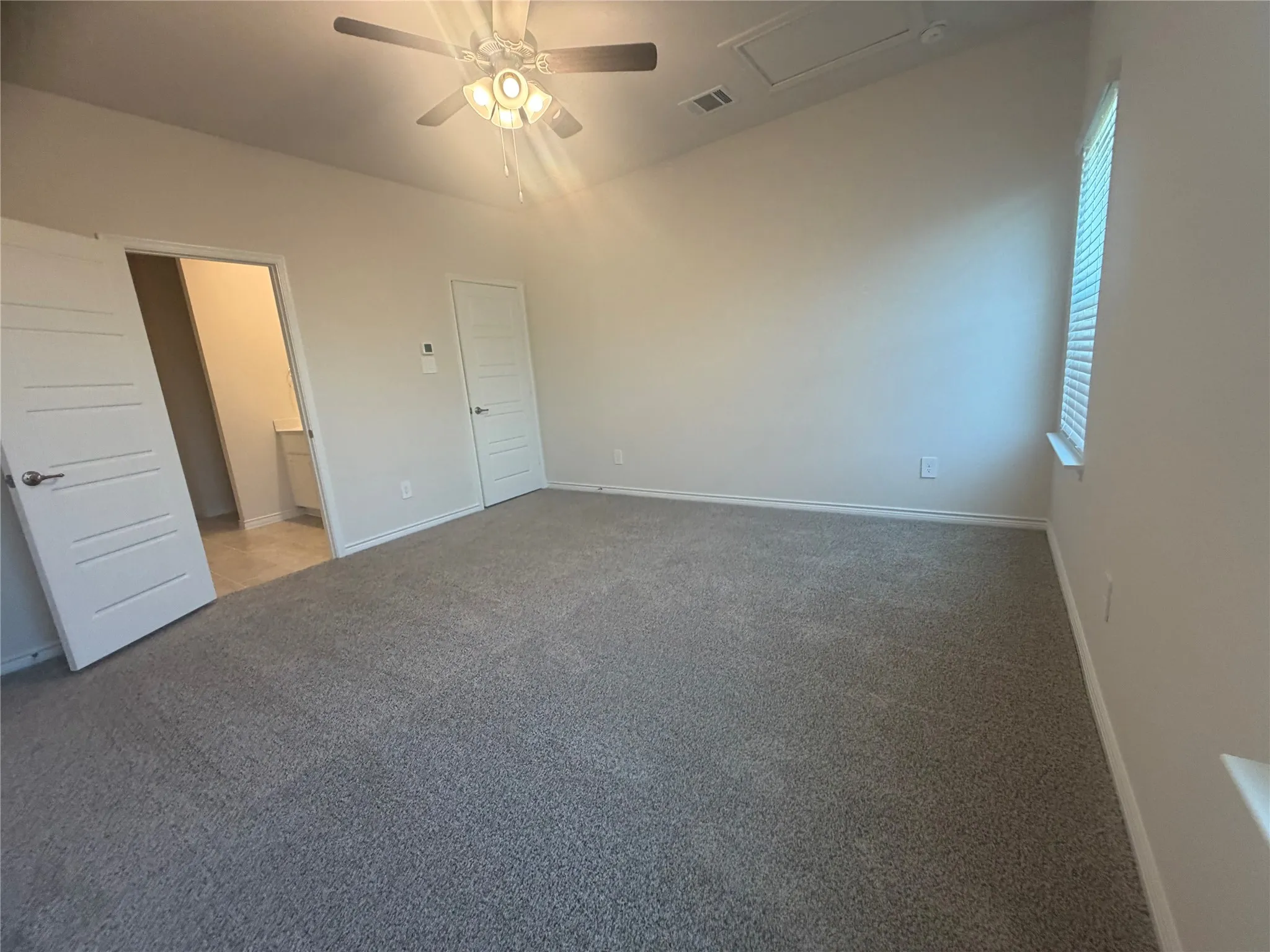 Vaulted ceiling, ceiling fan with integrated lighting, window with blinds, light gray wall paint, and gray carpet flooring