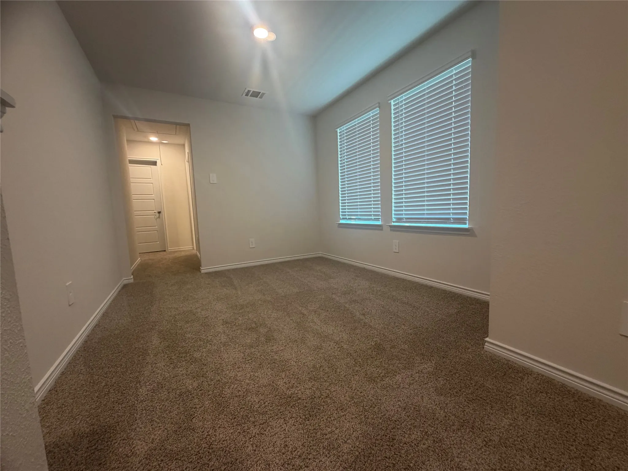 Carpeted room featuring multiple windows with blinds, recessed lighting, and a neutral wall palette