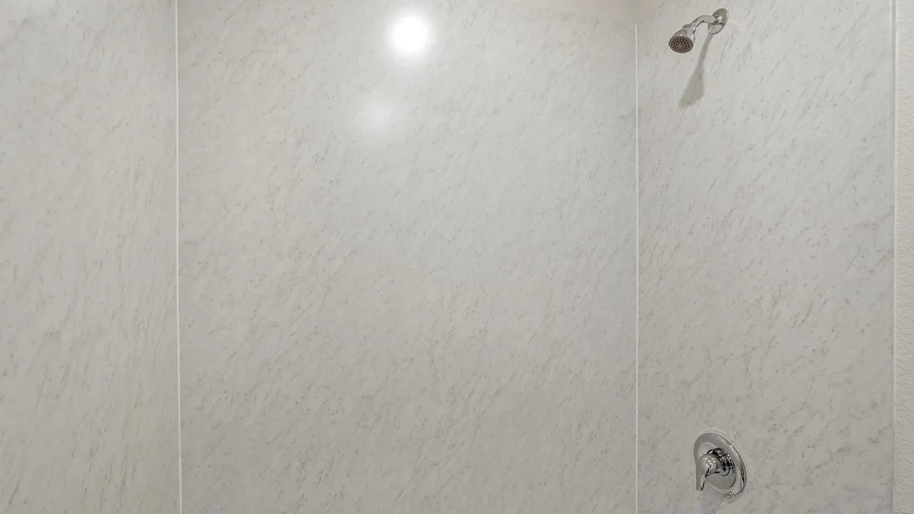 Shower enclosure with light-toned wall panels, chrome shower head, and chrome single-handle control