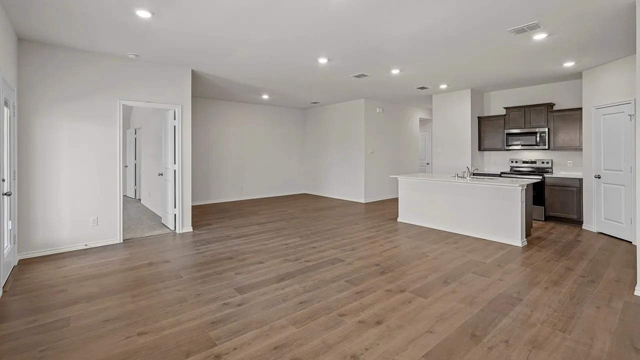 Expansive room featuring wood-finish flooring, recessed lighting, and a kitchen island with integrated sink