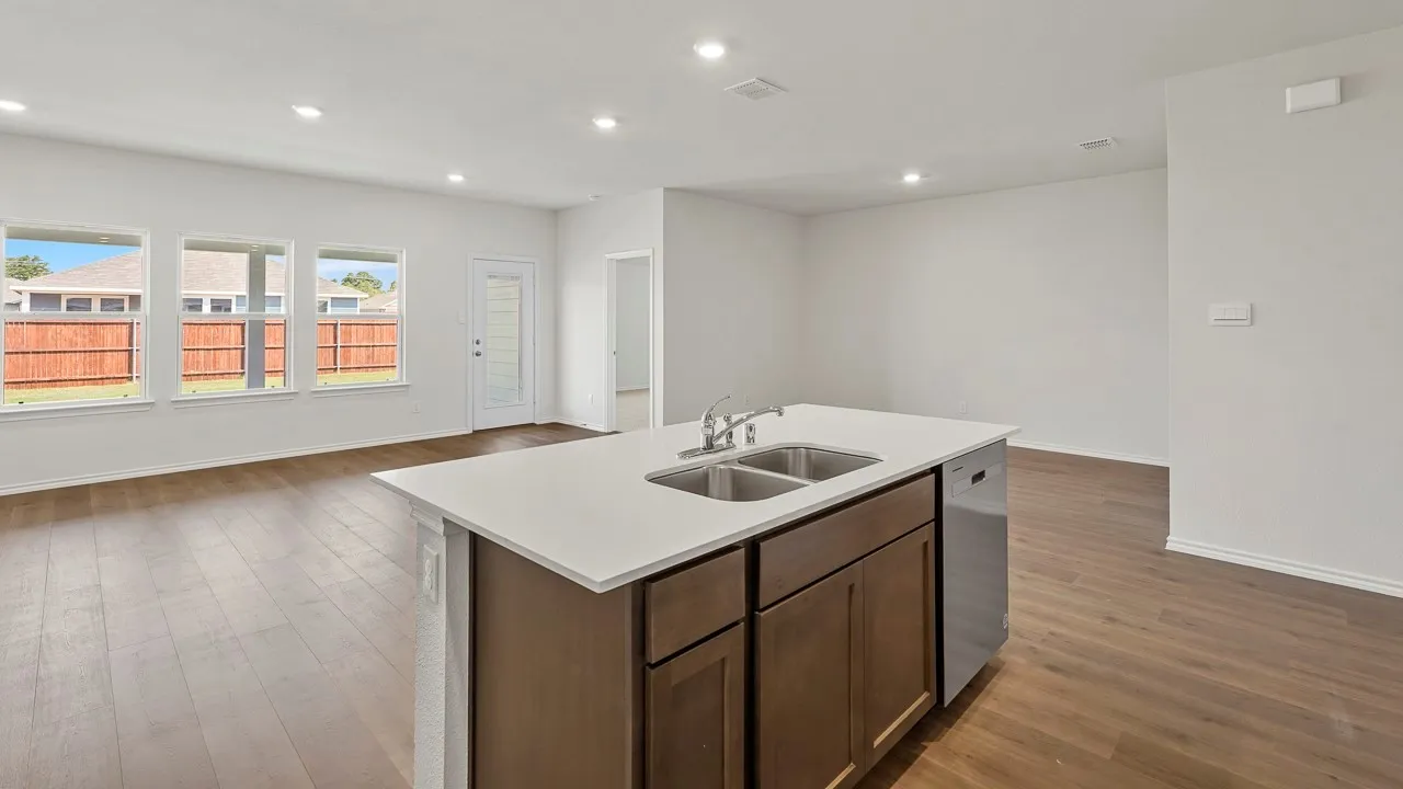 Kitchen island with dual stainless steel sinks, a built-in dishwasher, and a light-colored countertop