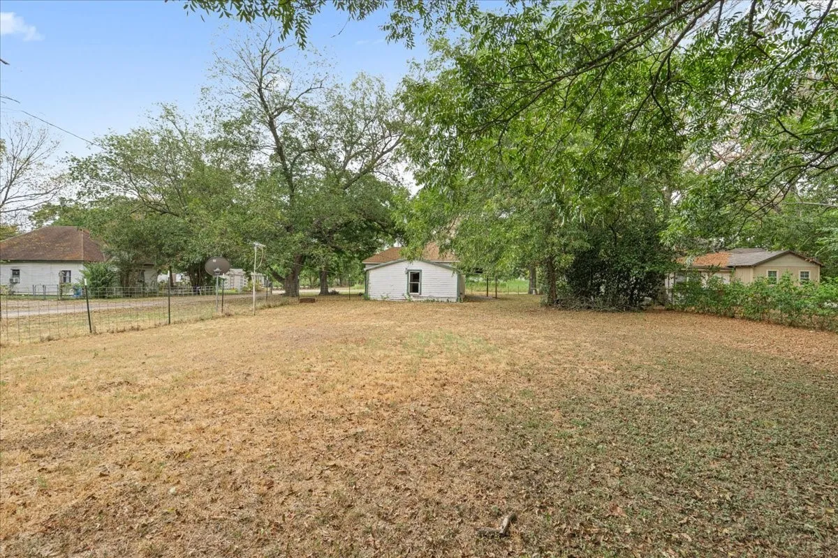 Expansive outdoor space featuring mature trees and a detached structure
