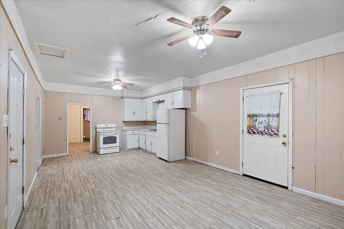 Wood-finish flooring, paneled walls, white cabinetry, and white appliances