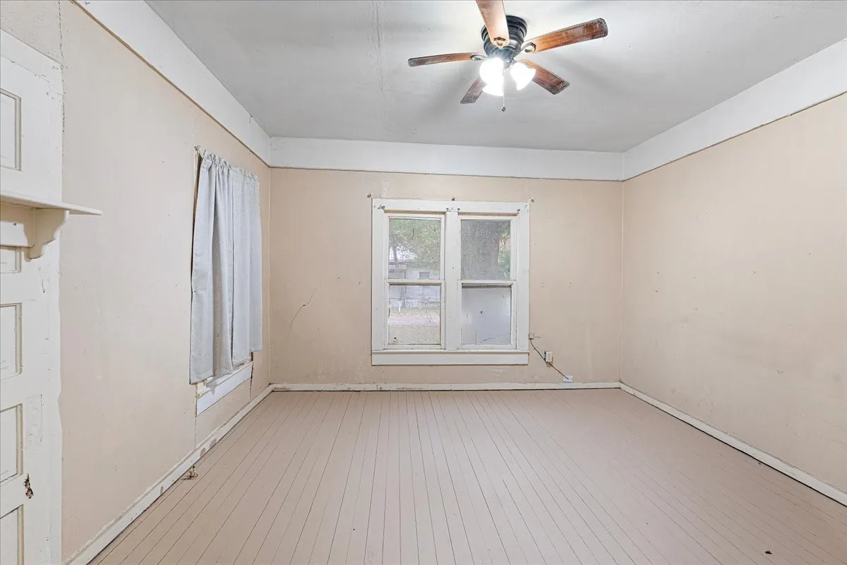 Wood-finish flooring with a ceiling fan light fixture and window