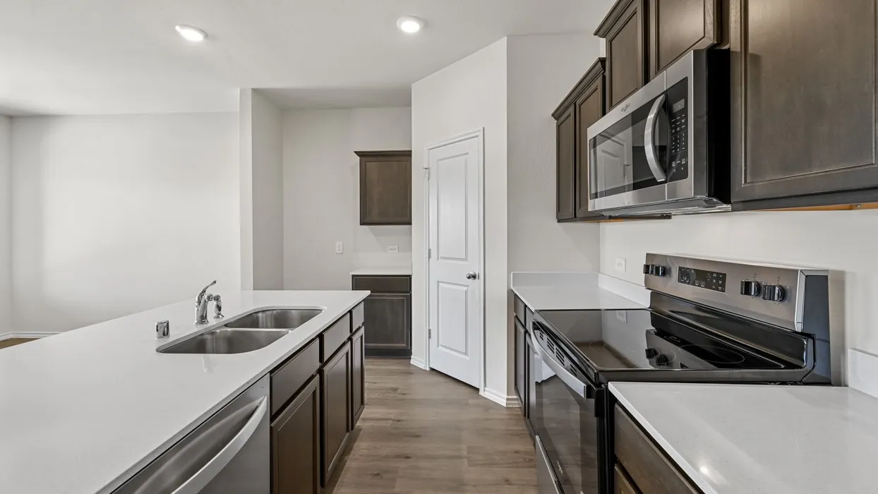 Modern kitchen featuring dark wood-finish cabinetry, stainless steel appliances, and light-toned countertops