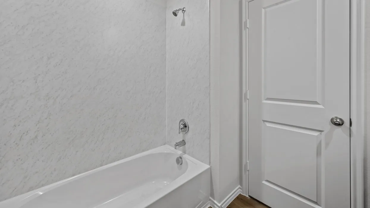 White bathtub and shower combination featuring a chrome showerhead and faucet