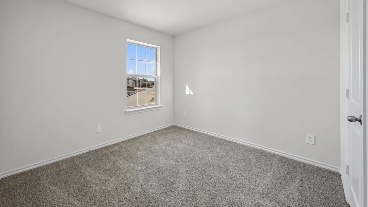 Carpeted interior room with neutral-toned walls, white trim, and a window with muntins