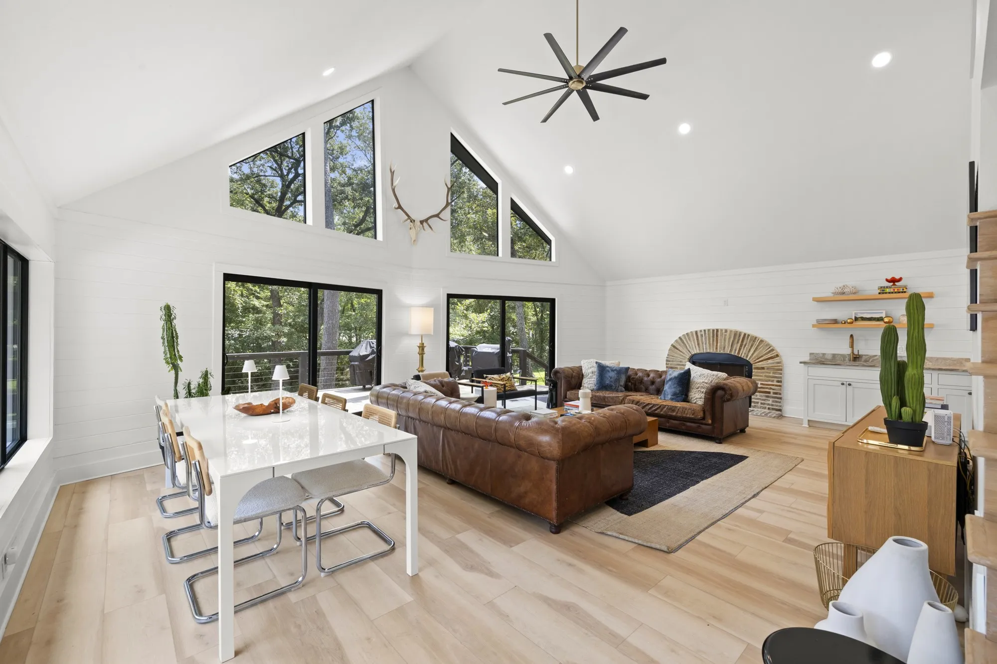 Living room with high vaulted ceiling, wood walls, recessed lighting, light wood-type flooring, and a fireplace