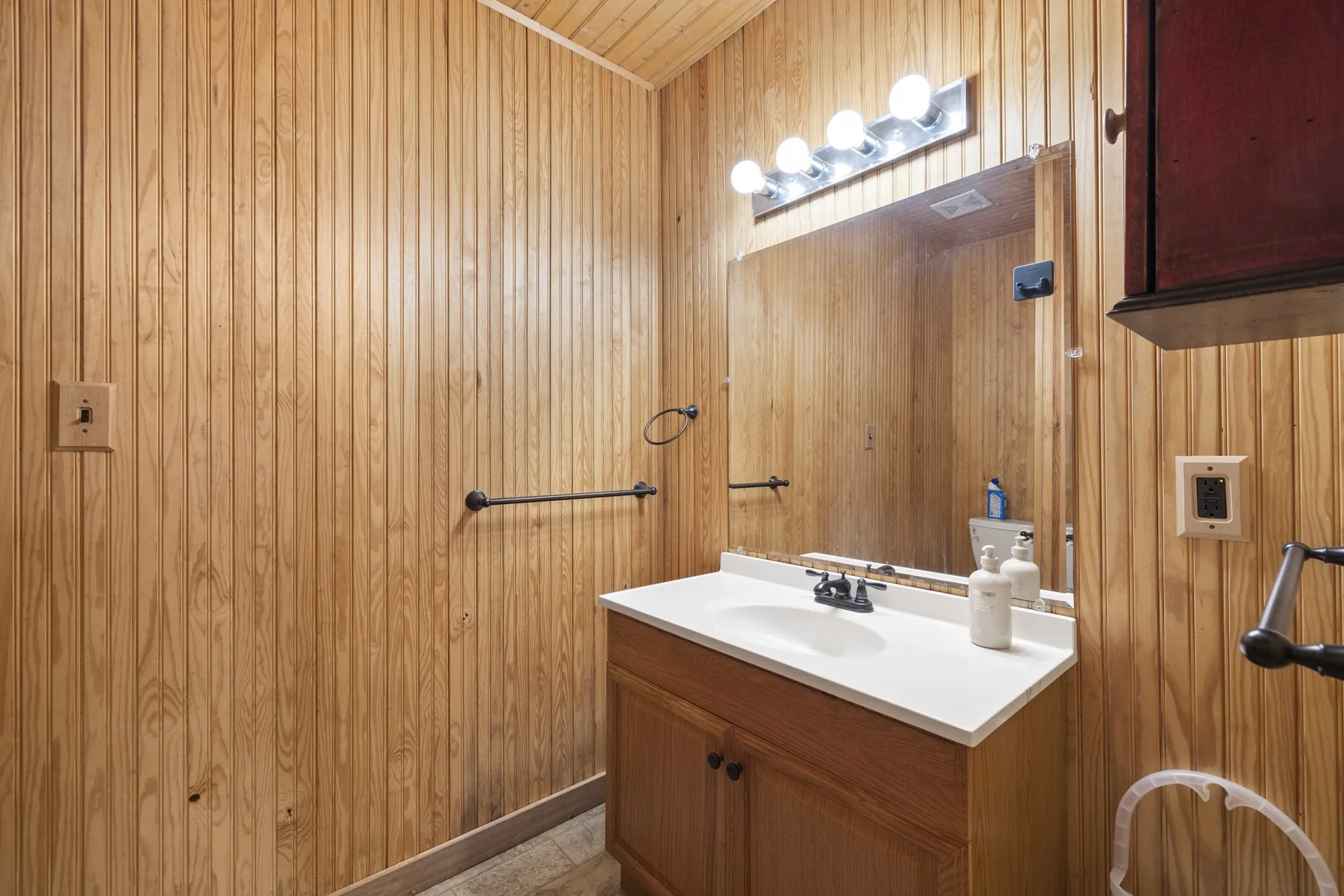 Half bath with vanity and wooden walls