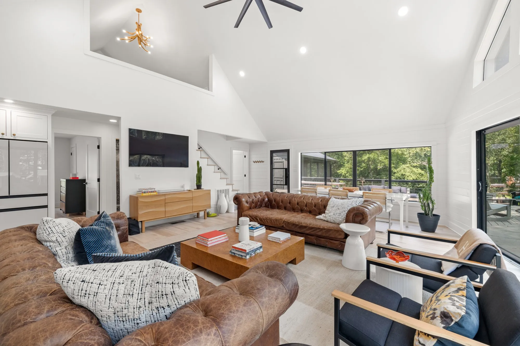 Living area with high vaulted ceiling, stairway, recessed lighting, wood finished floors, and a chandelier