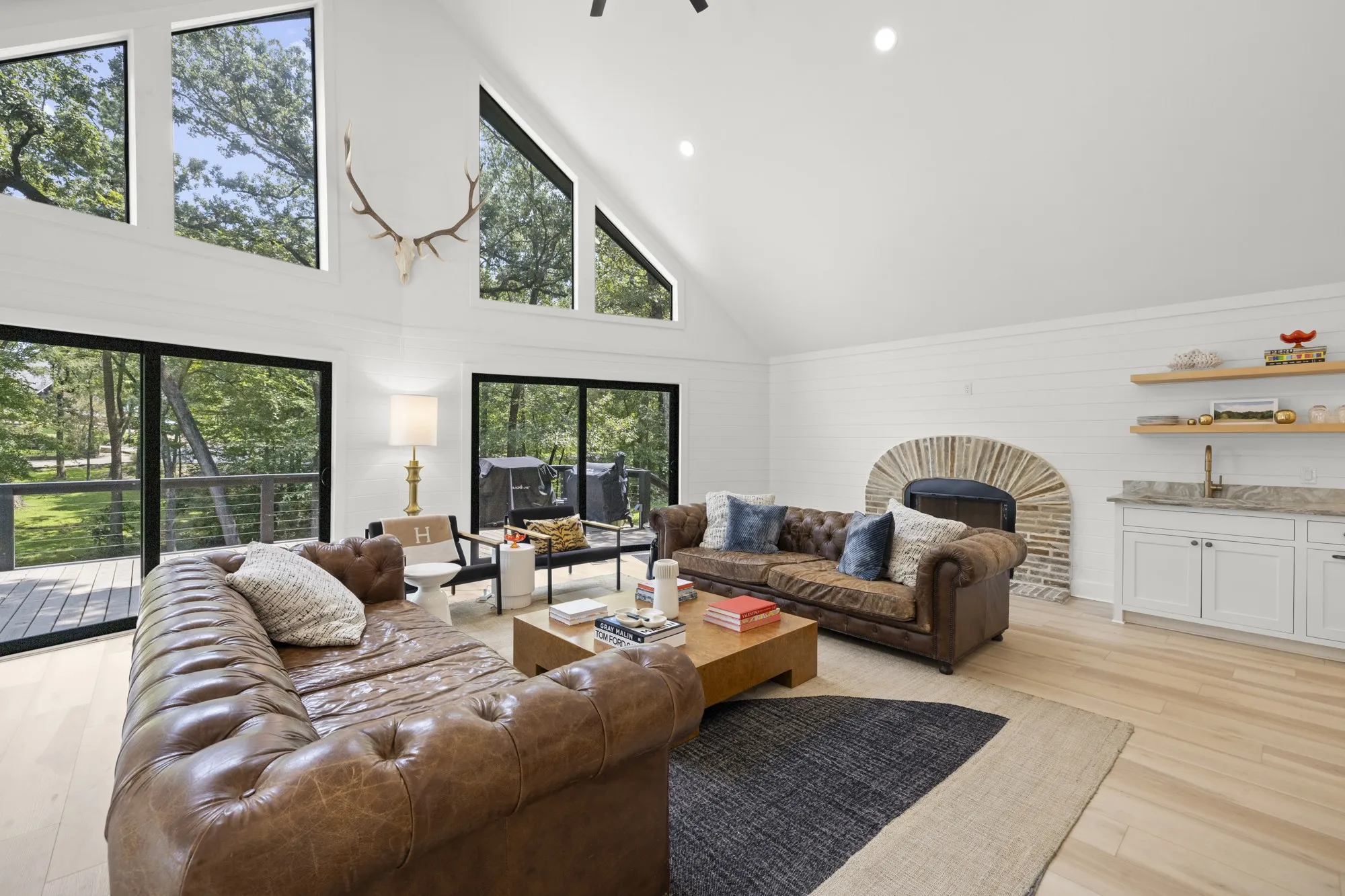 Living area with high vaulted ceiling, recessed lighting, light wood-style floors, and wooden walls