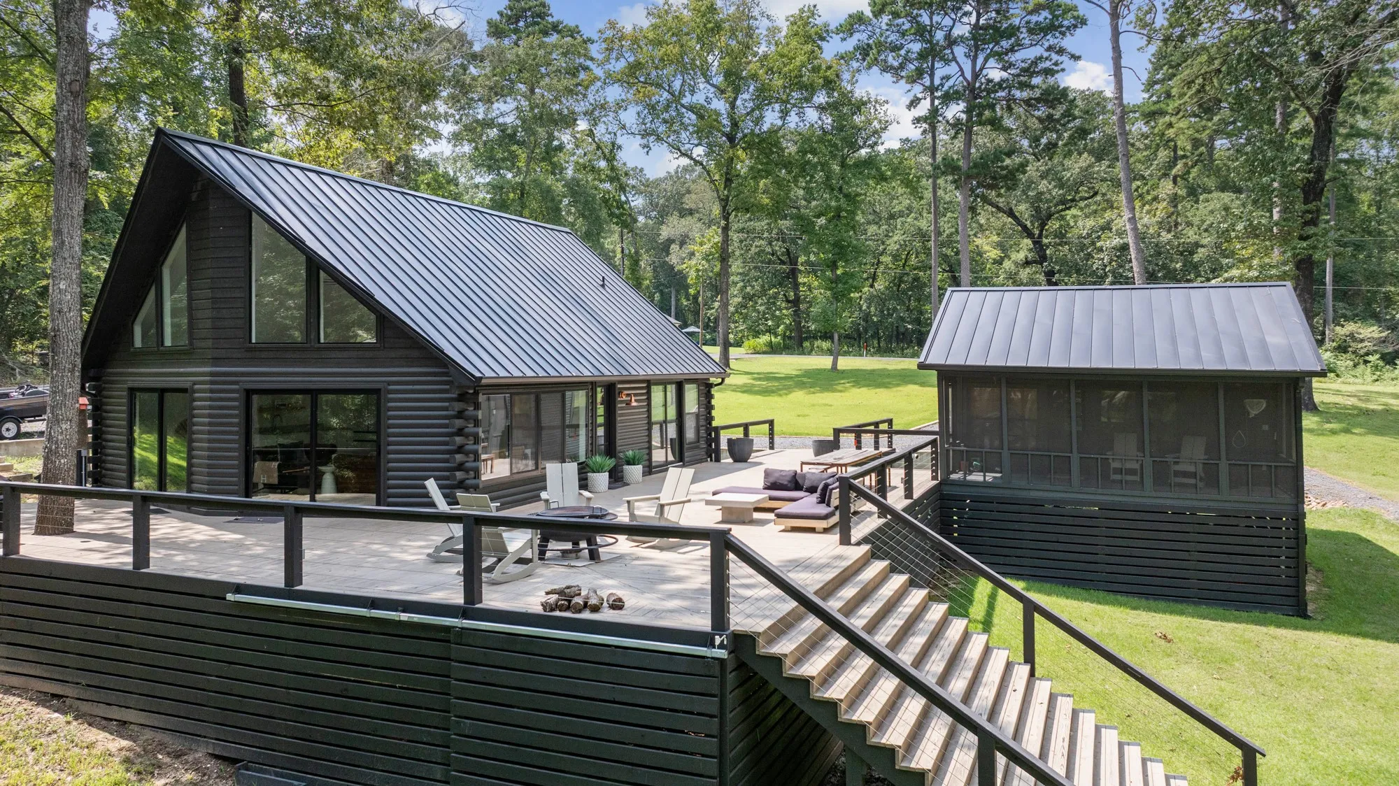 Deck featuring a yard, view of scattered trees, a sunroom, a patio, and stairway
