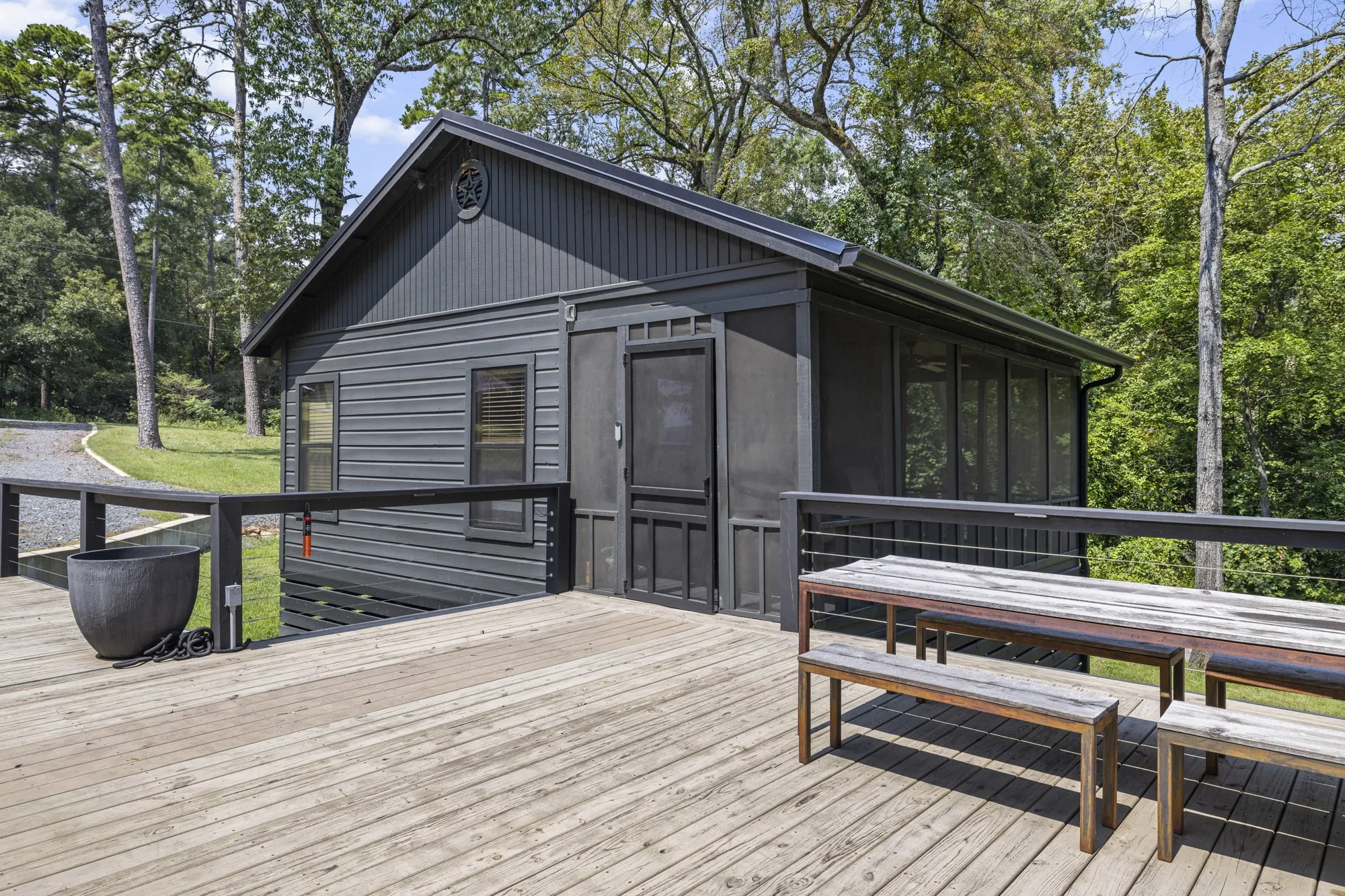 Deck with a sunroom, outdoor dining space, and view of scattered trees