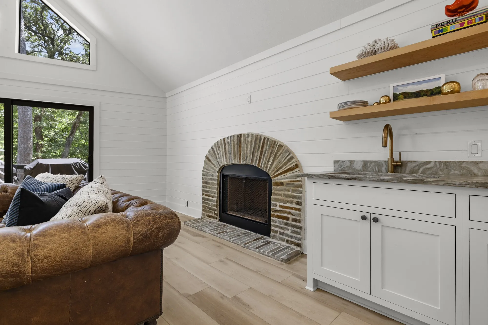 Living area with light wood-type flooring, high vaulted ceiling, a fireplace, and wood walls