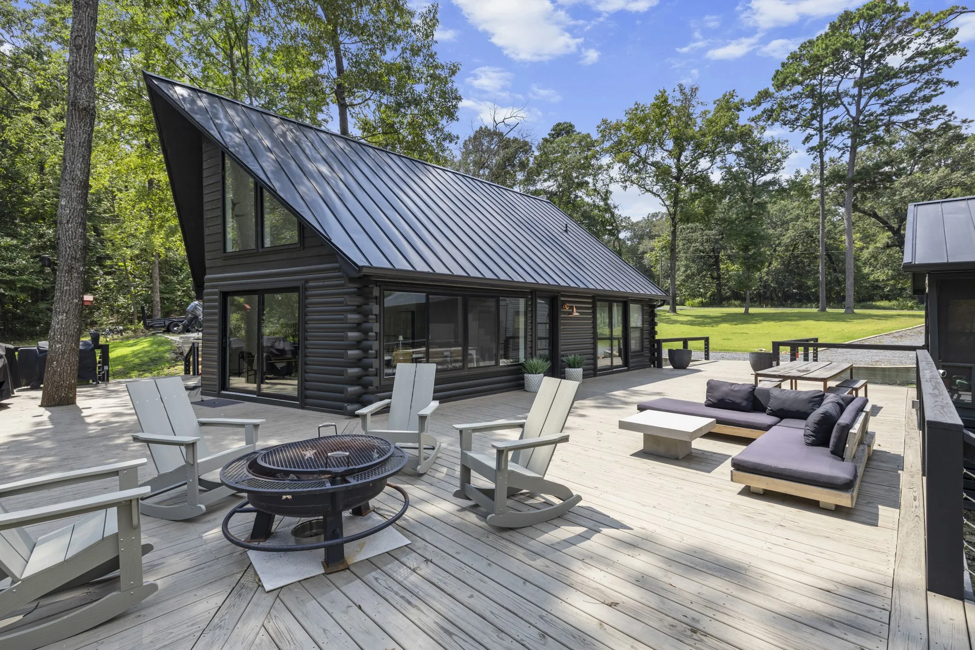 Wooden deck with an outdoor living space with a fire pit, a sunroom, and view of wooded area