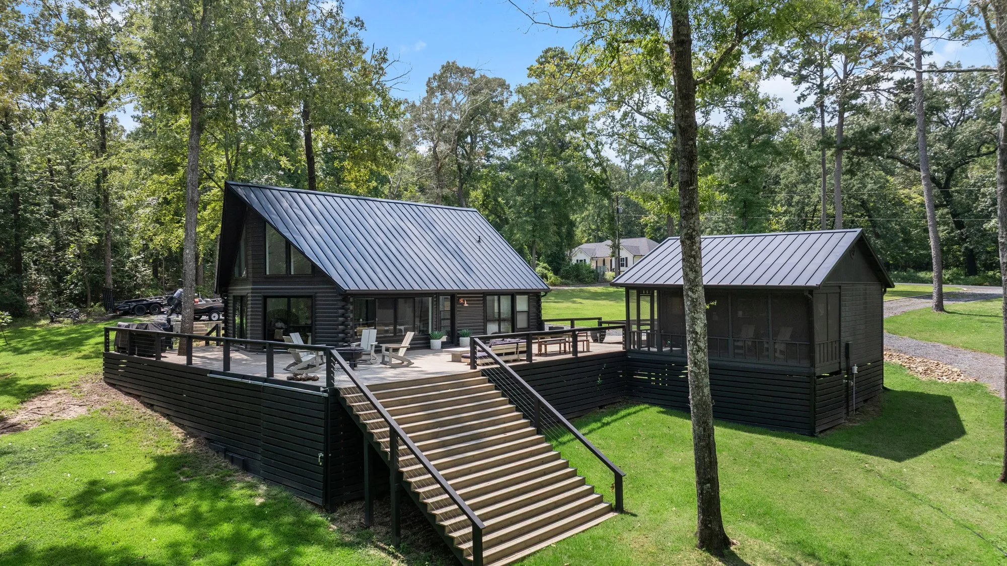 Rear view of property featuring a wooden deck, a metal roof, a sunroom, and a lawn