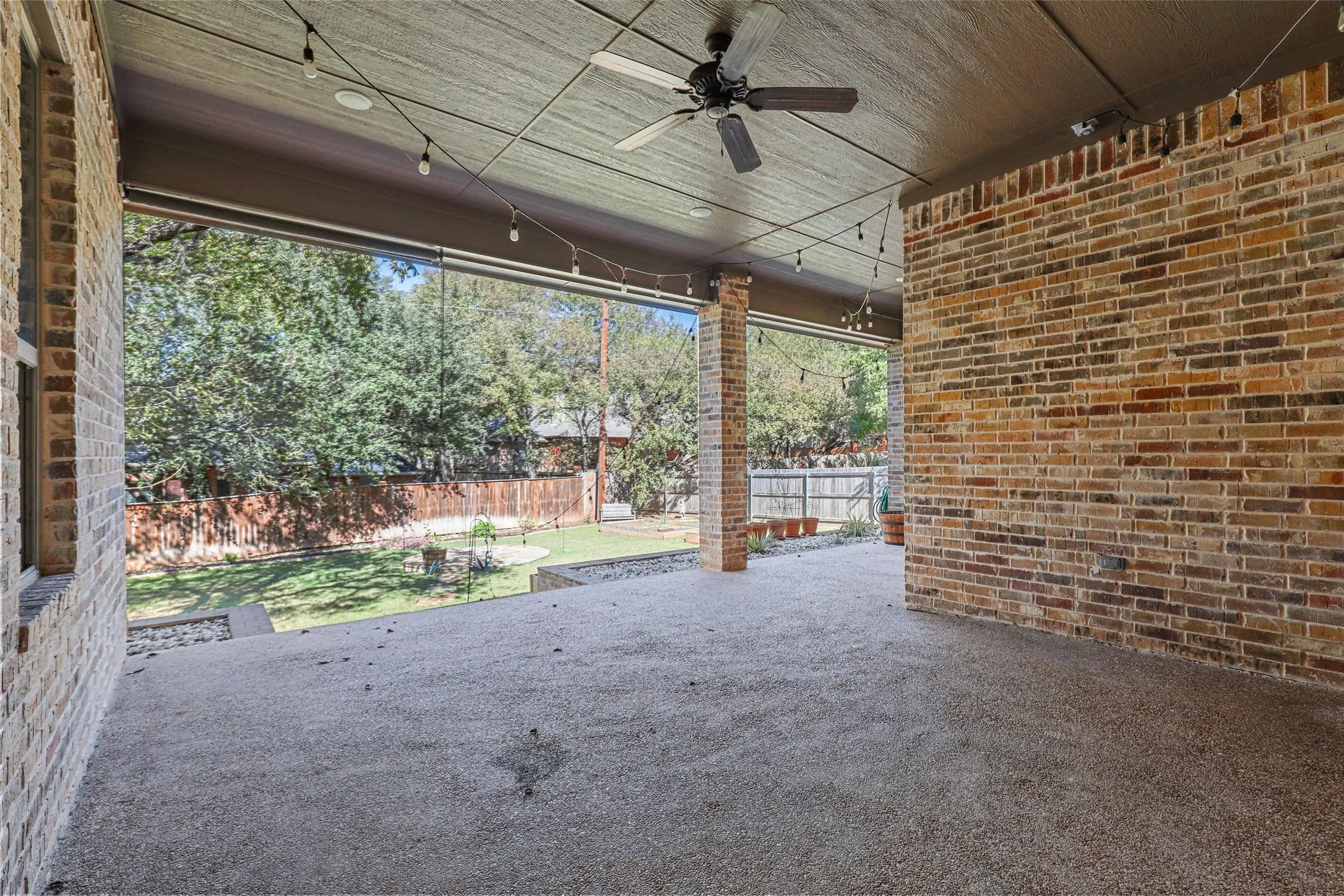 Expansive covered patio with brick columns, recessed lighting, and a ceiling fan