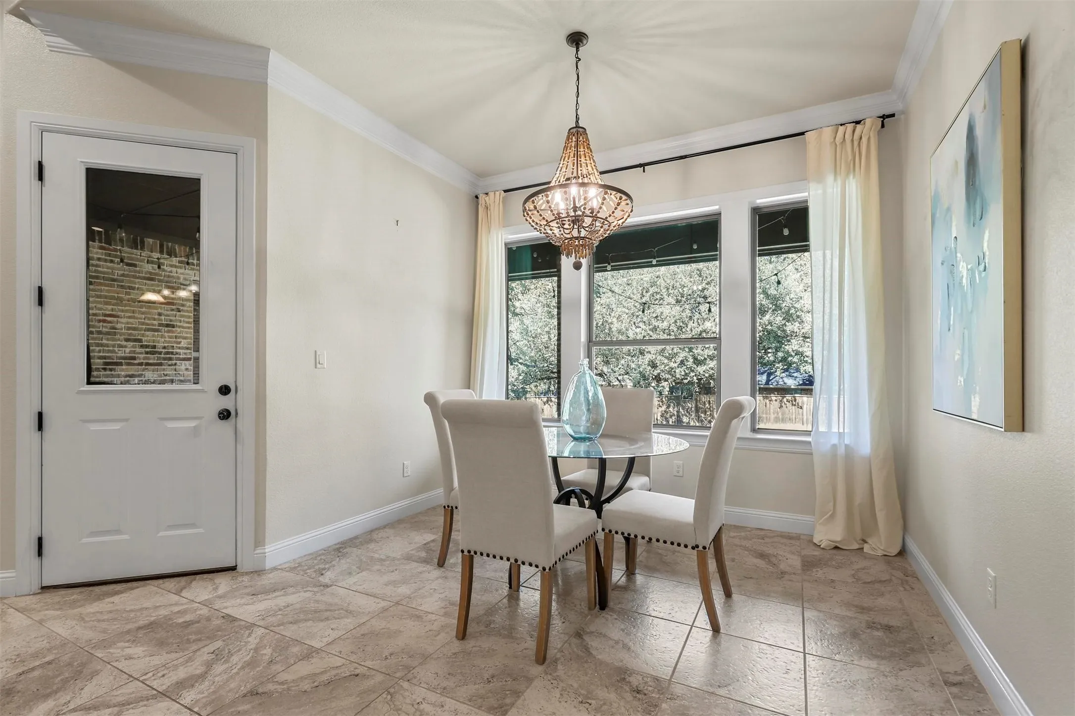 Neutral wall paint, crown molding, glass-paned door, large windows, and tile flooring