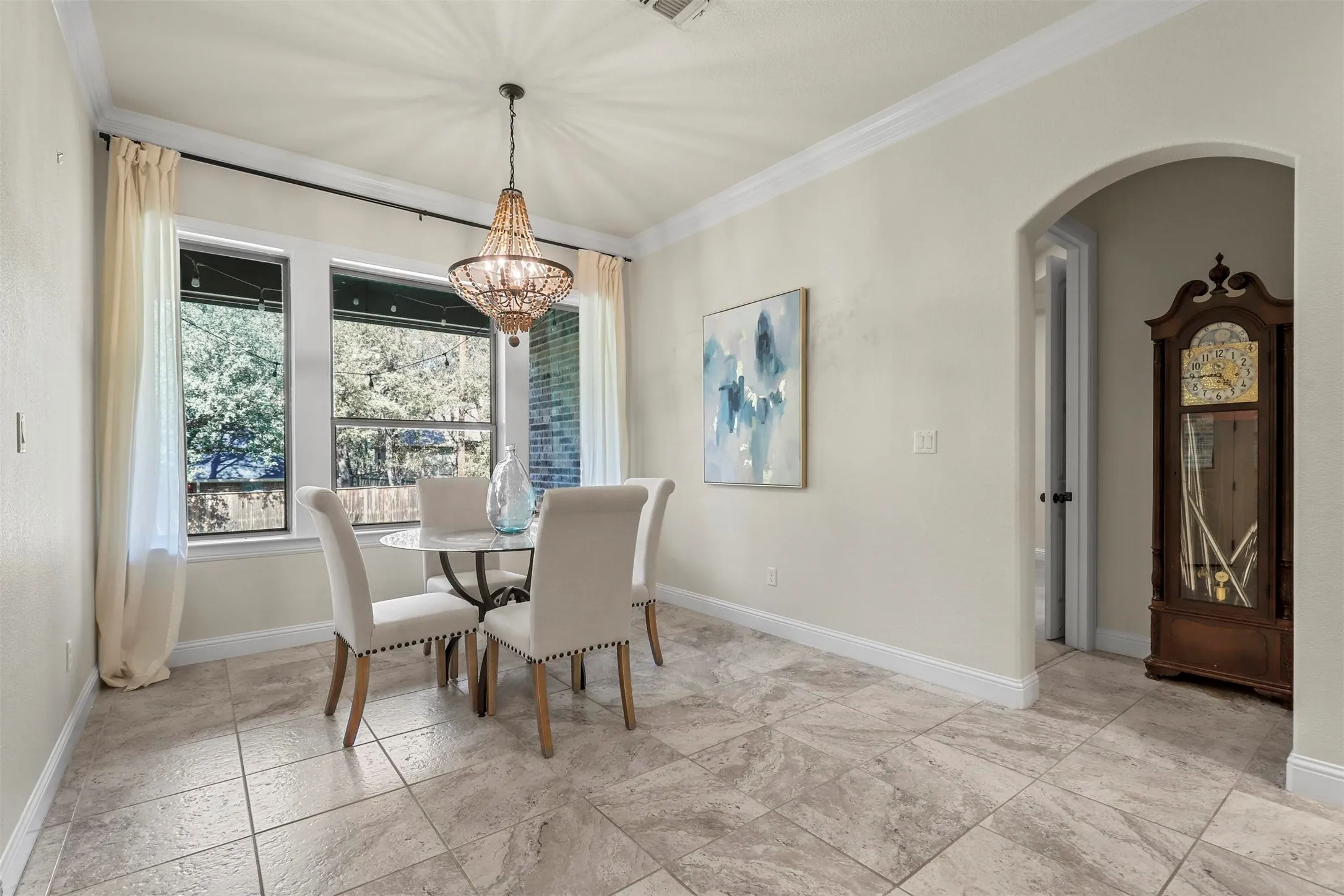 Tile flooring, multiple windows, decorative chandelier, crown molding, arched doorway
