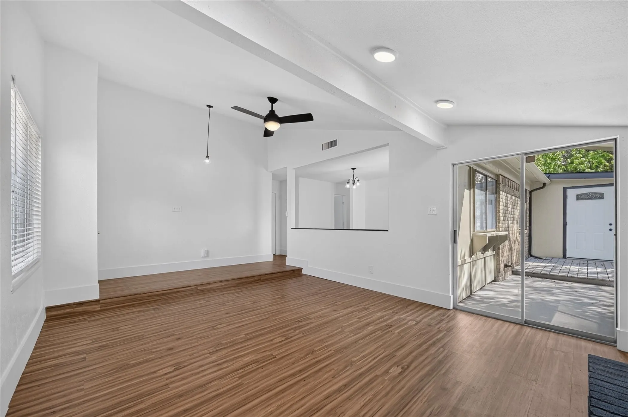 Vaulted ceiling, wood-finish flooring, recessed lighting, ceiling fan, and sliding glass door