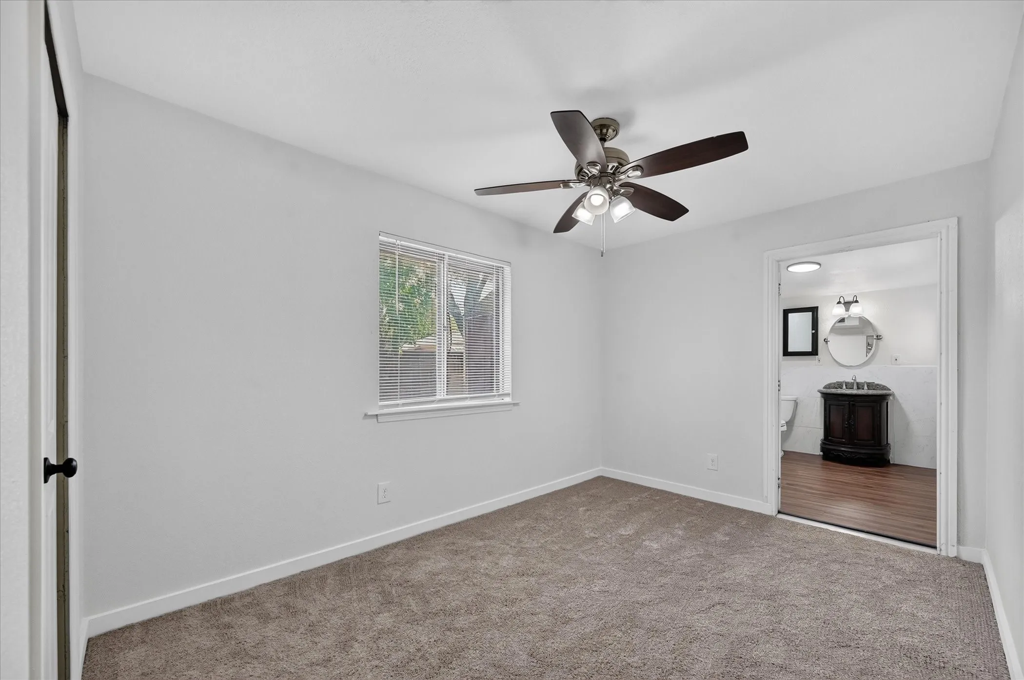 Carpeted flooring, ceiling fan with integrated lighting, and a white-framed window
