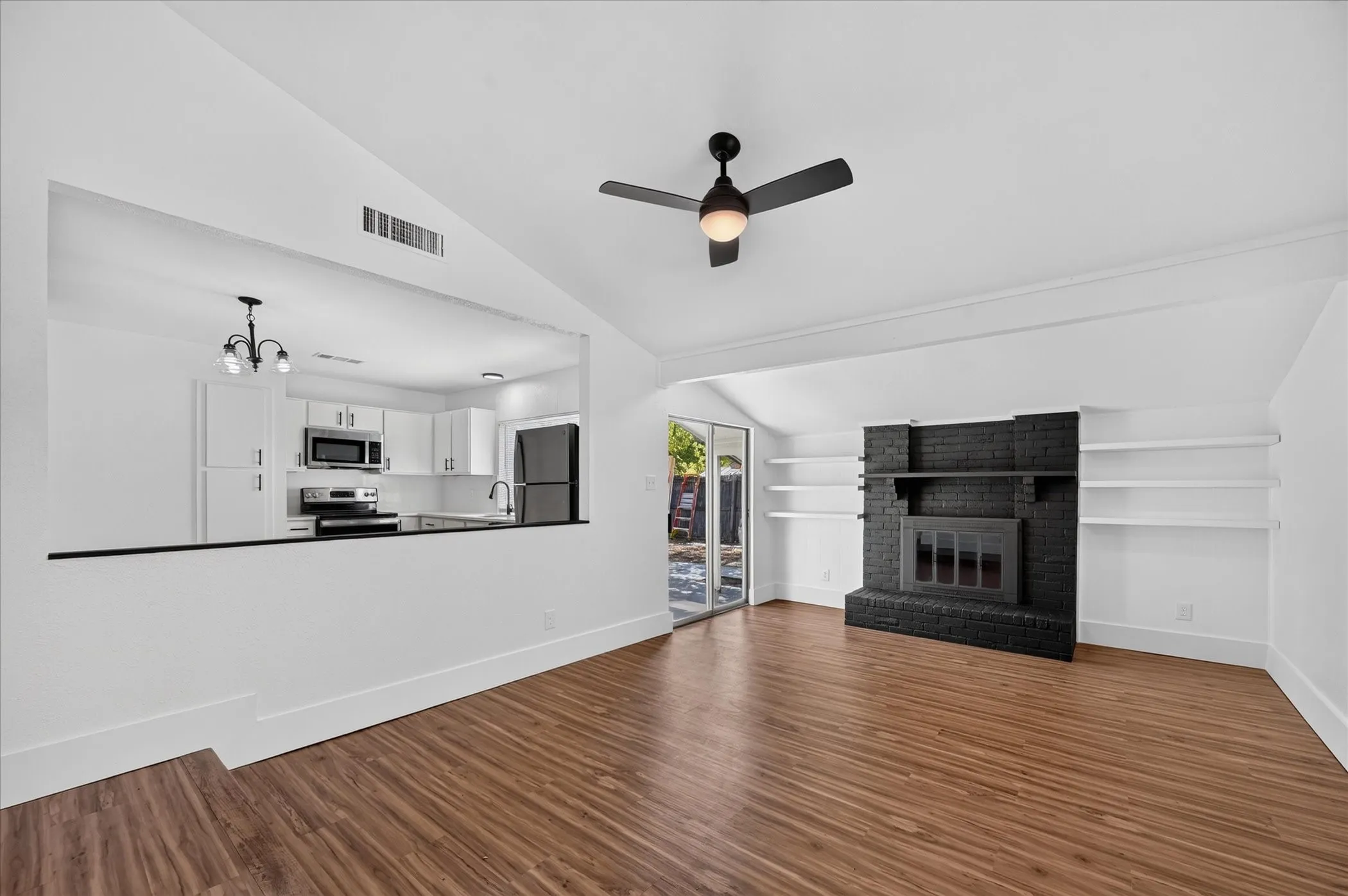 Vaulted ceilings, wood-finish flooring, and a brick fireplace with built-in shelving