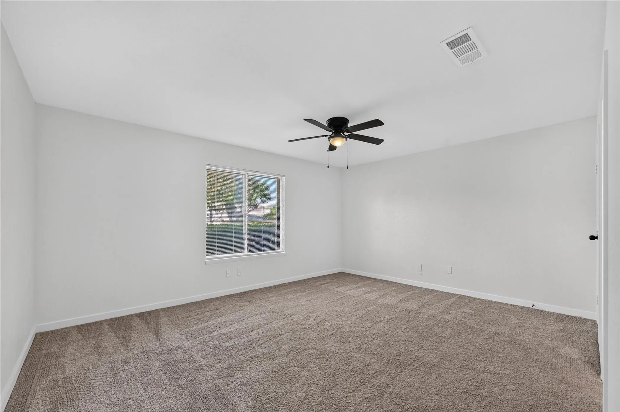 Spacious room featuring neutral carpet and a window with natural light