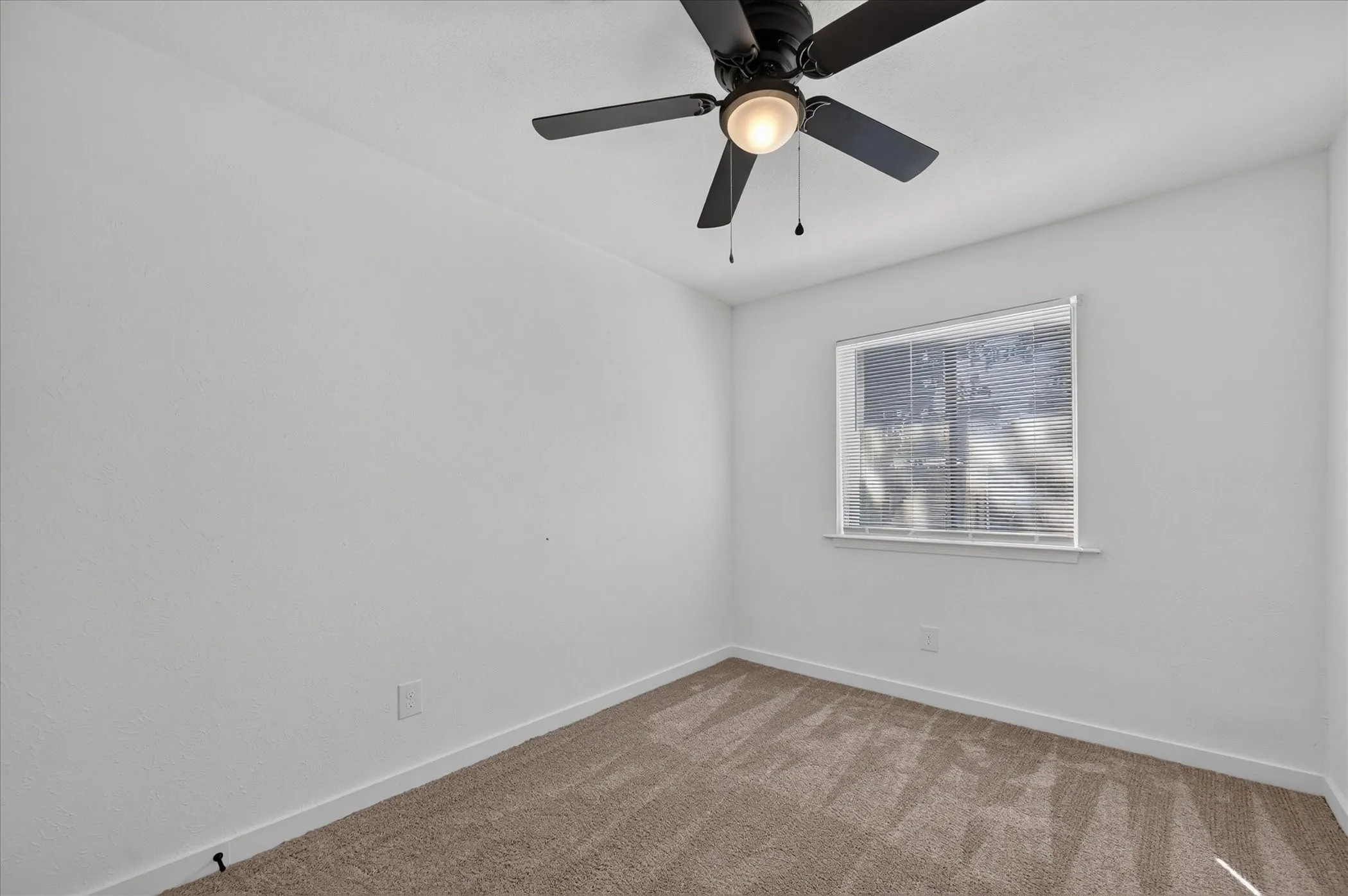 Neutral wall paint, window with blinds, ceiling fan with integrated lighting, and carpeted flooring