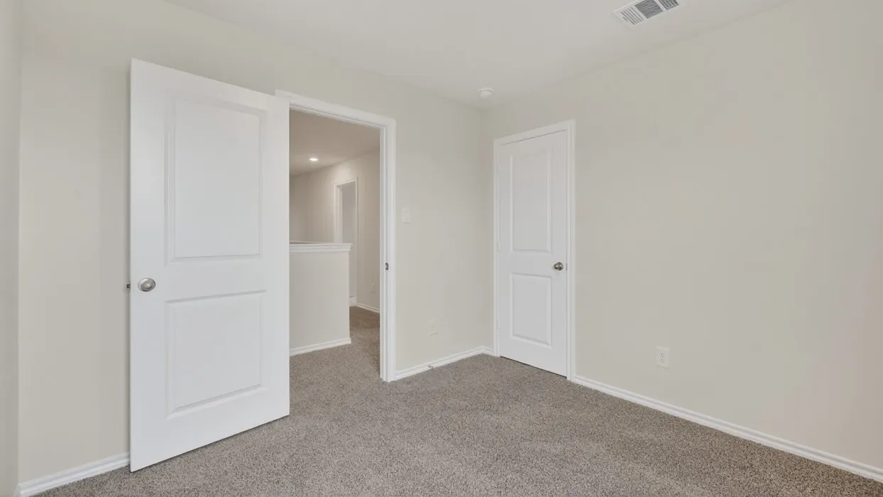 Carpeted room featuring light neutral wall paint, white baseboards, and white two-panel interior doors with brushed nickel hardware