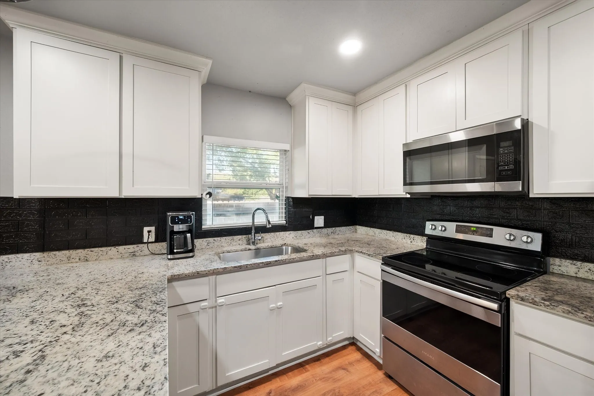L shaped kitchen with granite countertops and stainless steel appliances