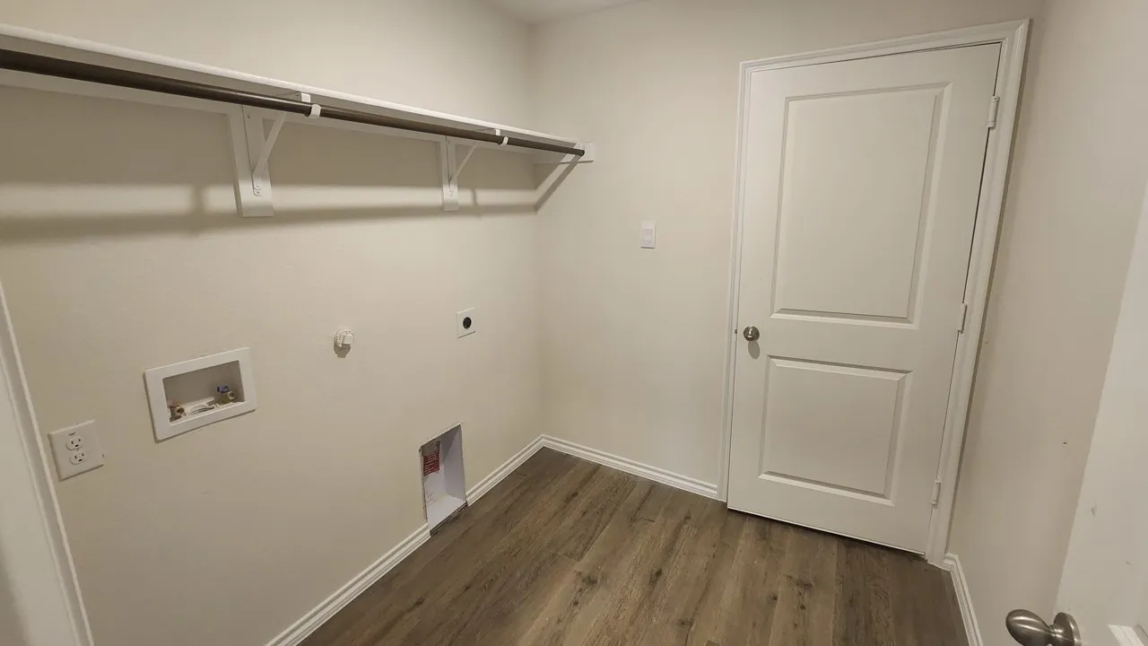 Dedicated utility space featuring wood-finish flooring, white baseboards, and a neutral wall color
