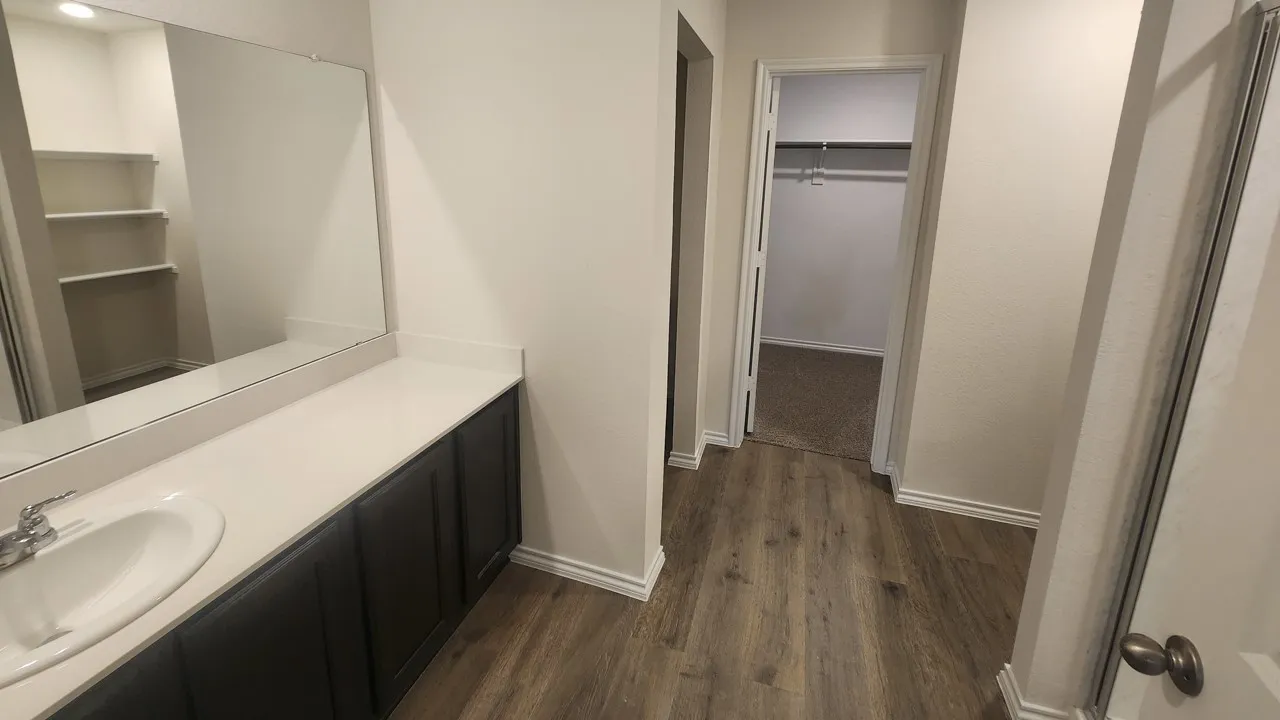 Bathroom vanity with a white oval sink, chrome faucet, and expansive wall-mounted mirror