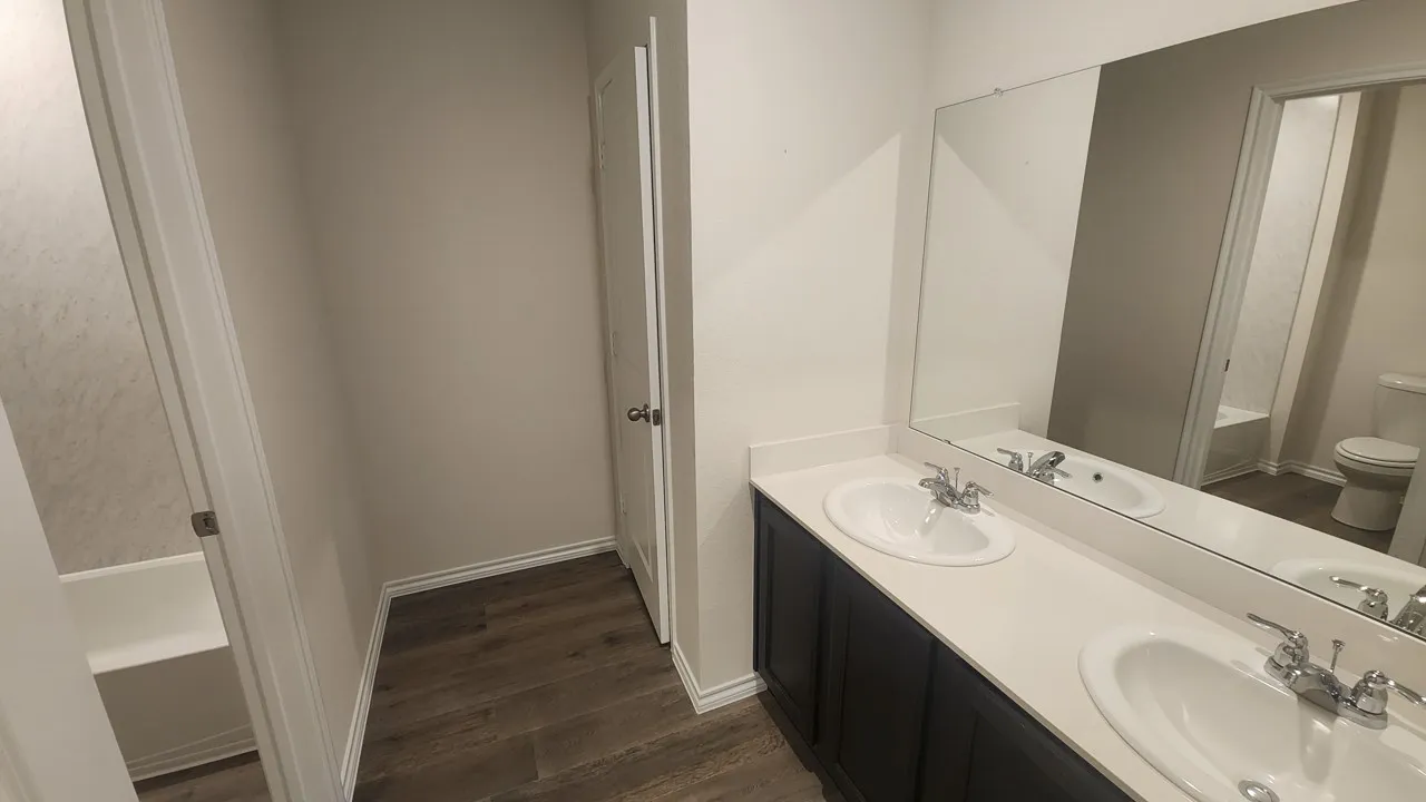 Bathroom vanity featuring dual undermount sinks, chrome fixtures, and a white countertop