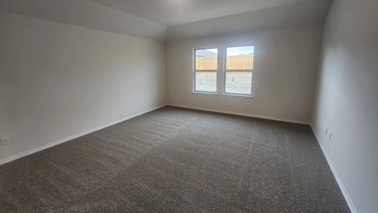 Spacious room featuring neutral carpeting, light-toned walls, and a tray ceiling