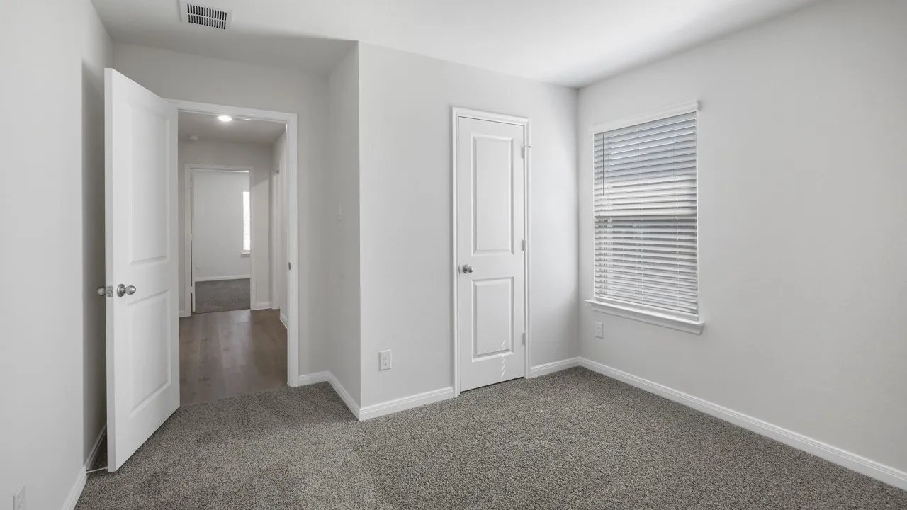 Carpeted room featuring a white interior door, a window with horizontal blinds, and light gray walls