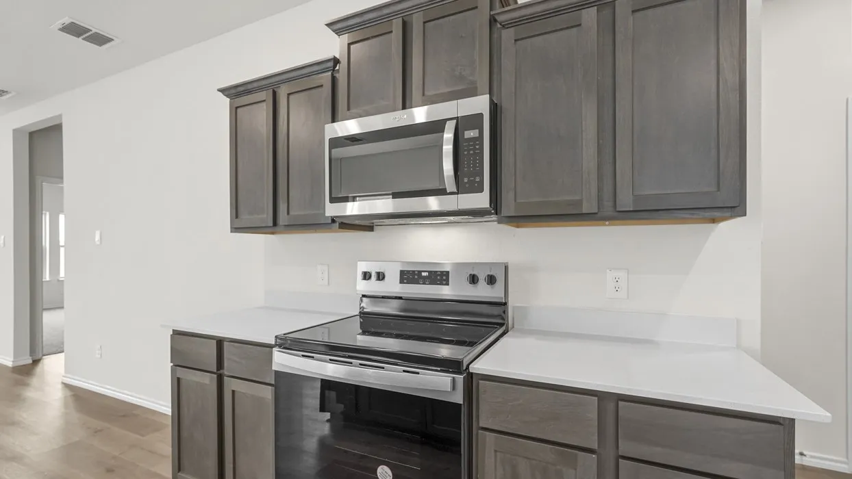 Kitchen space featuring dark wood-finish cabinetry, light countertops, and a stainless steel range with an overhead microwave