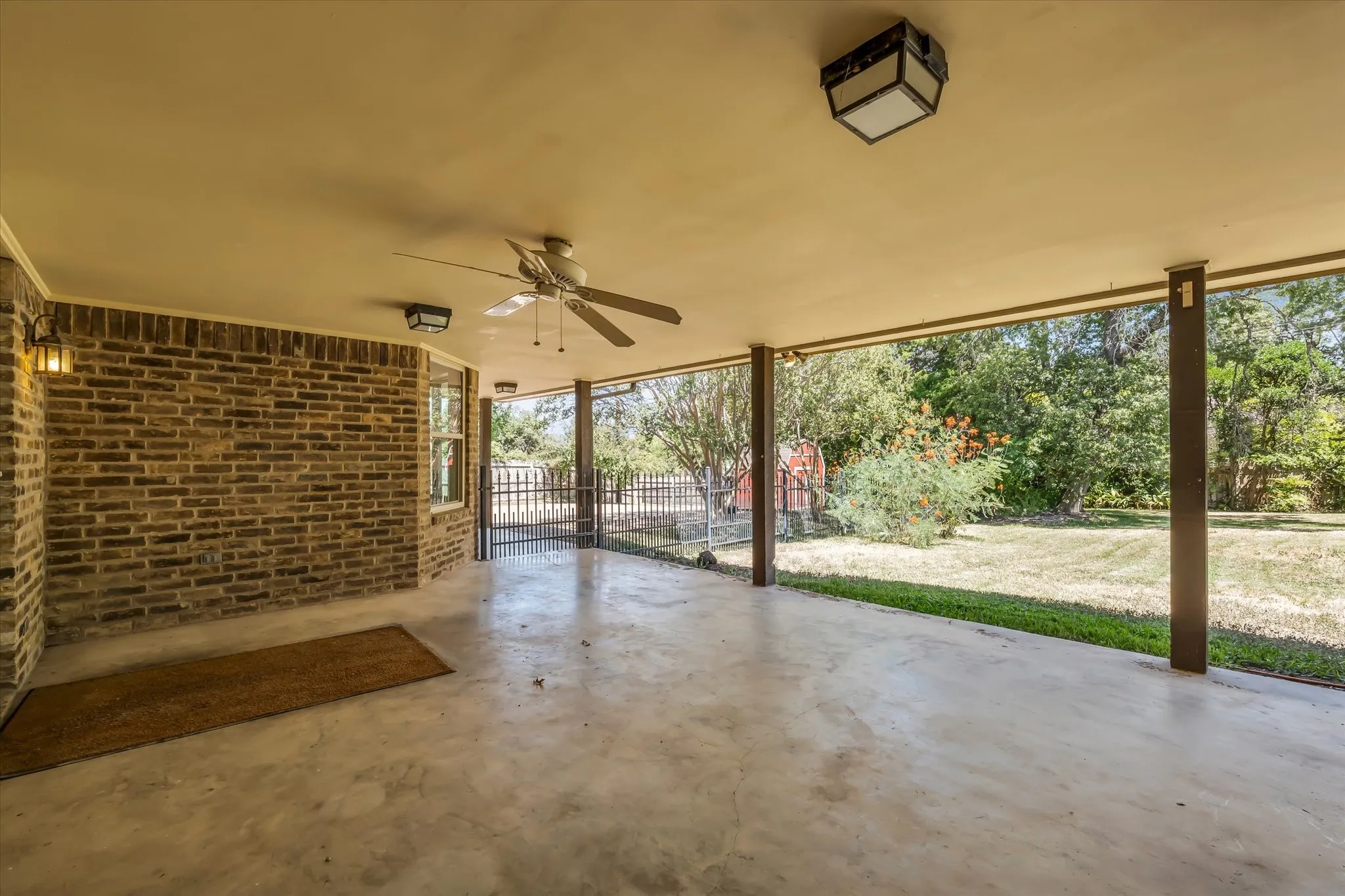 Covered patio featuring concrete flooring, a ceiling fan, and brick wall construction