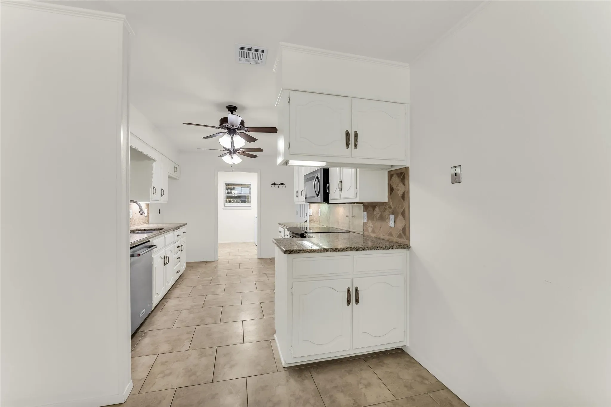 Kitchen featuring white cabinetry, stone countertops, tile backsplash, and tile flooring