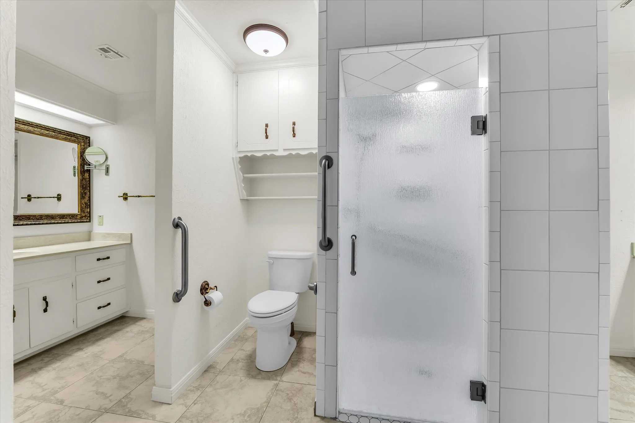 White vanity with ample drawer storage, built-in medicine cabinet with shelving, privacy glass shower enclosure, and tiled shower walls