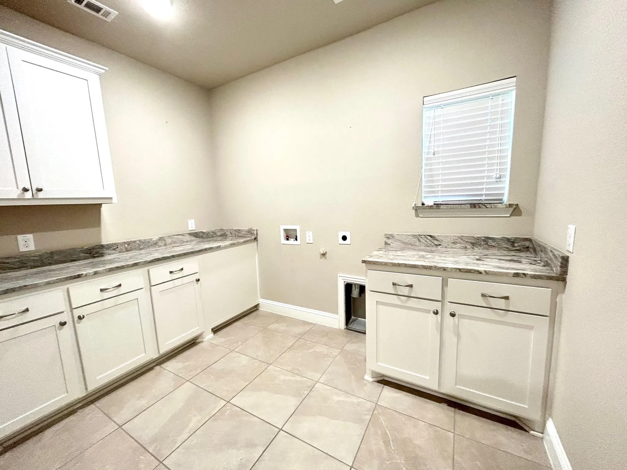 Laundry room has lots of storage cabinets and room for folding clothes.