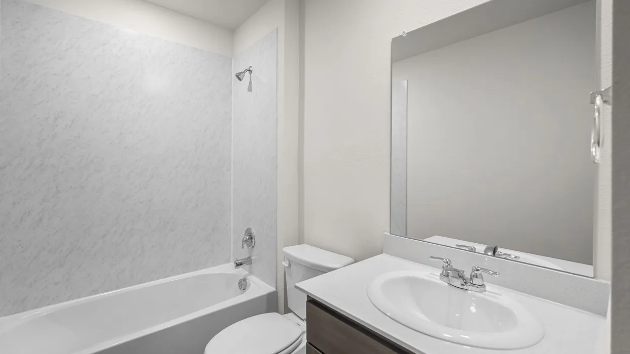 Bathroom featuring a white tub with a patterned shower surround, chrome fixtures, and a white toilet