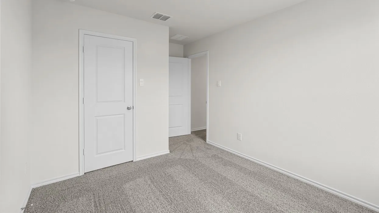 Interior room featuring light gray carpeting, white walls, white trim, and a white two-panel interior door with a brushed nickel knob