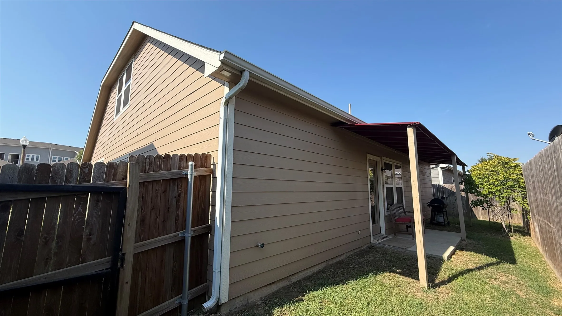 Exterior featuring horizontal siding, white trim, a gabled roofline, and a covered patio with concrete flooring